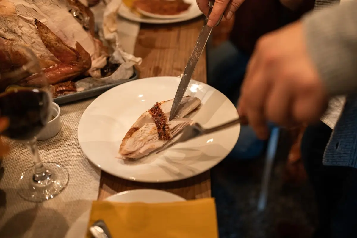 Czy pies może jeść wędlinę: deska z szynką i kiełbasą obok siedzącego dobermana